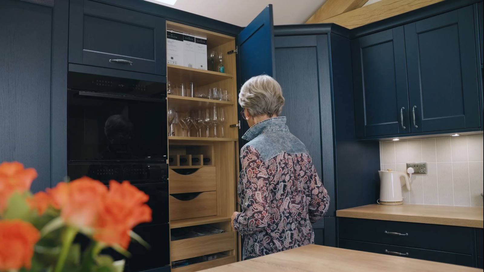 Edwina demonstrating a kitchen storage cabinet in the form of a kitchen pantry