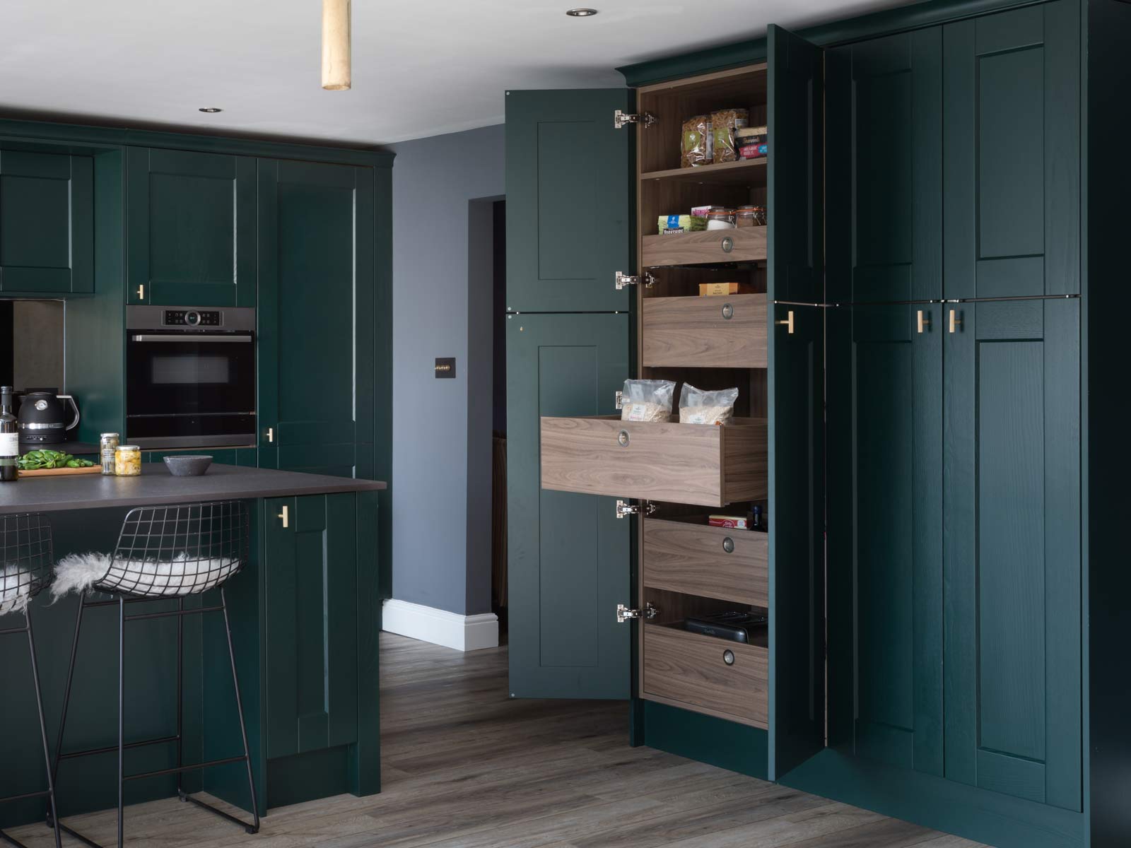 Green kitchen with a pantry with dark wood shelves