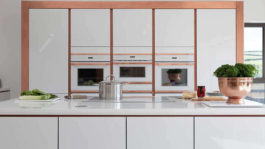 A handleless gloss kitchen with rose gold handlerails