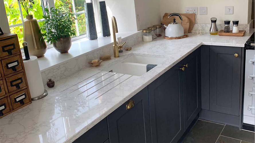 Brass handles and tap in a dark shaker kitchen