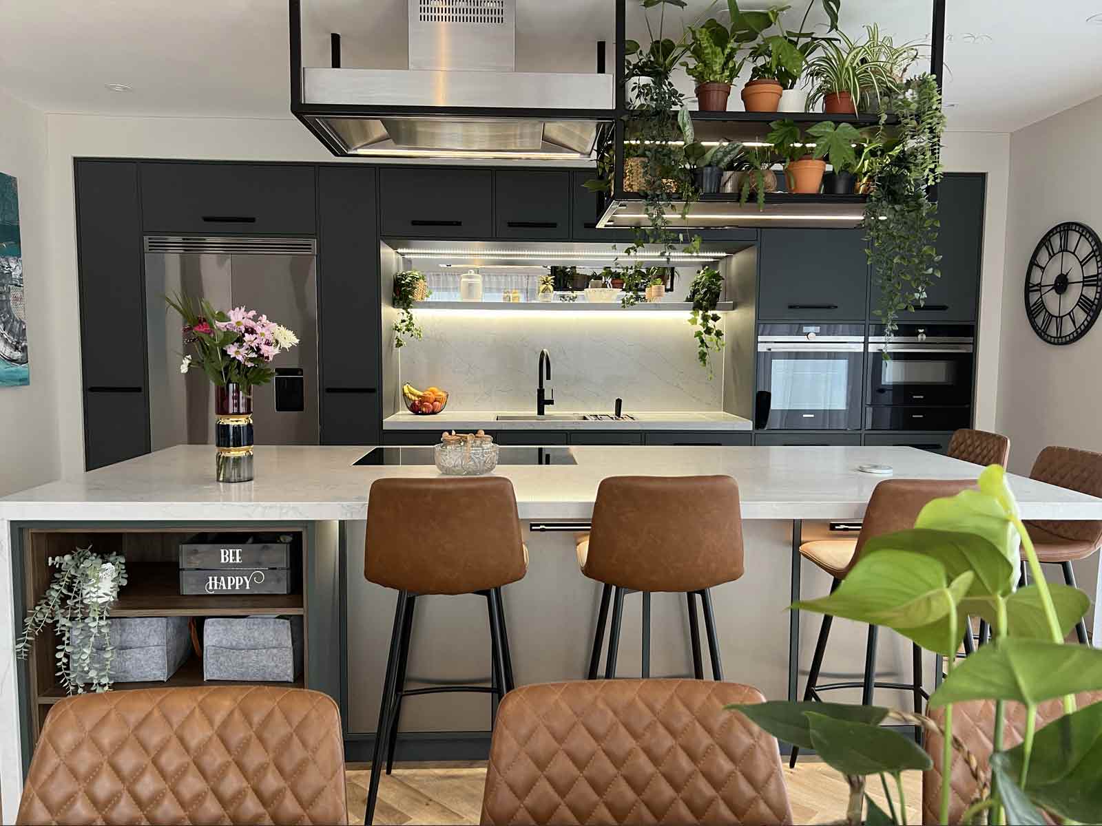 A kitchen with a biophilic design, including plants hanging front the ceiling
