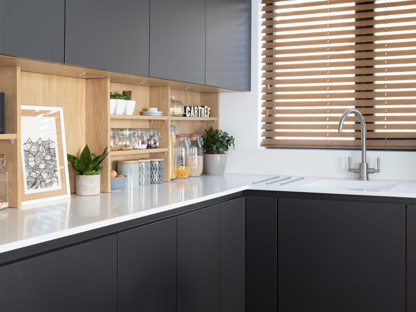 Light oak wood amidst kitchen shelving with black kitchen units