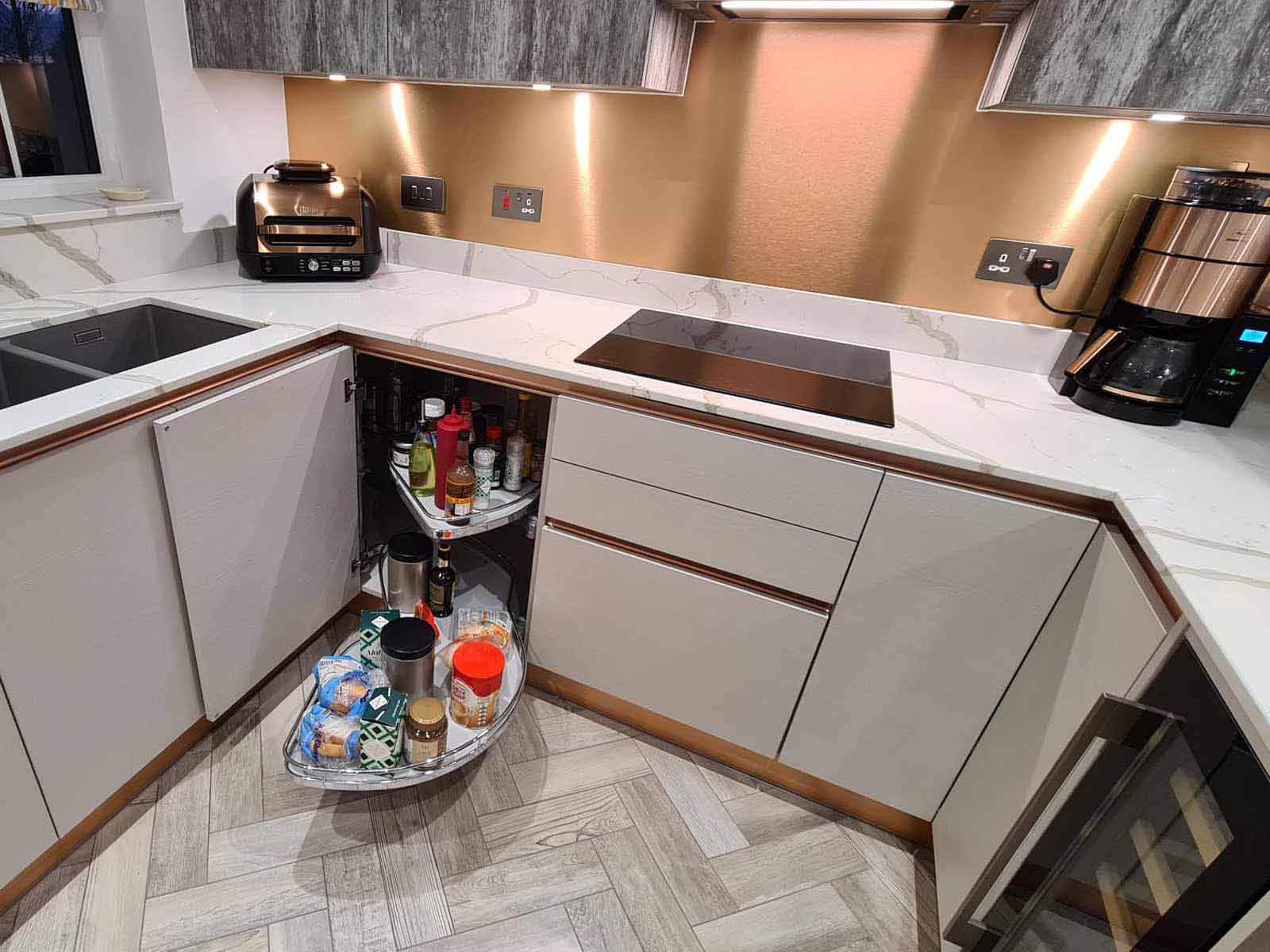 A cashmere-style kitchen with handleless doors and a bronze splashback