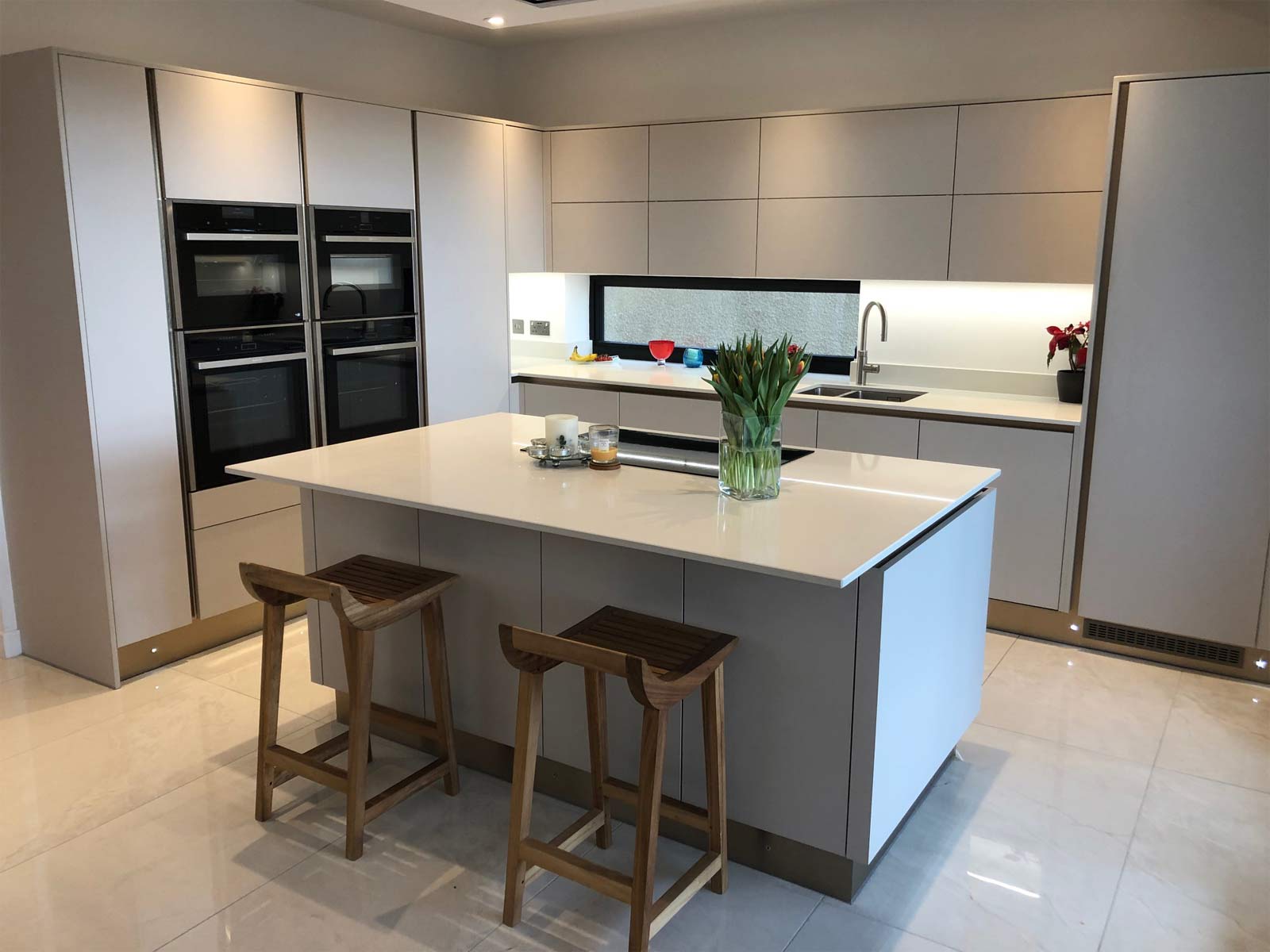 A cashmere kitchen with handleless grey cabinet doors and a kitchen island