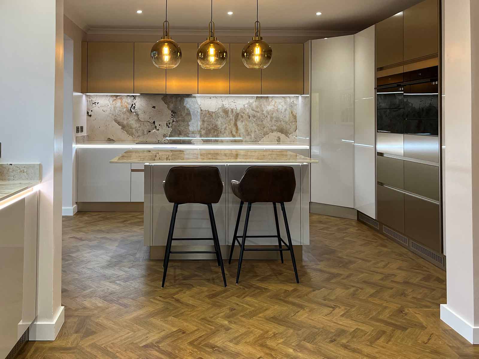 A handleless gloss cashmere kitchen with a wood flooring