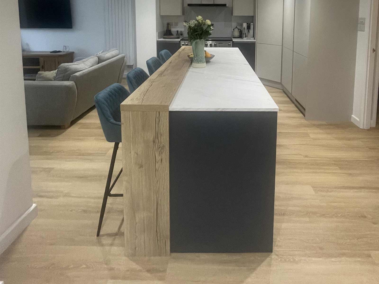 A two-tone kitchen island with a wood and marble counter and dark doors
