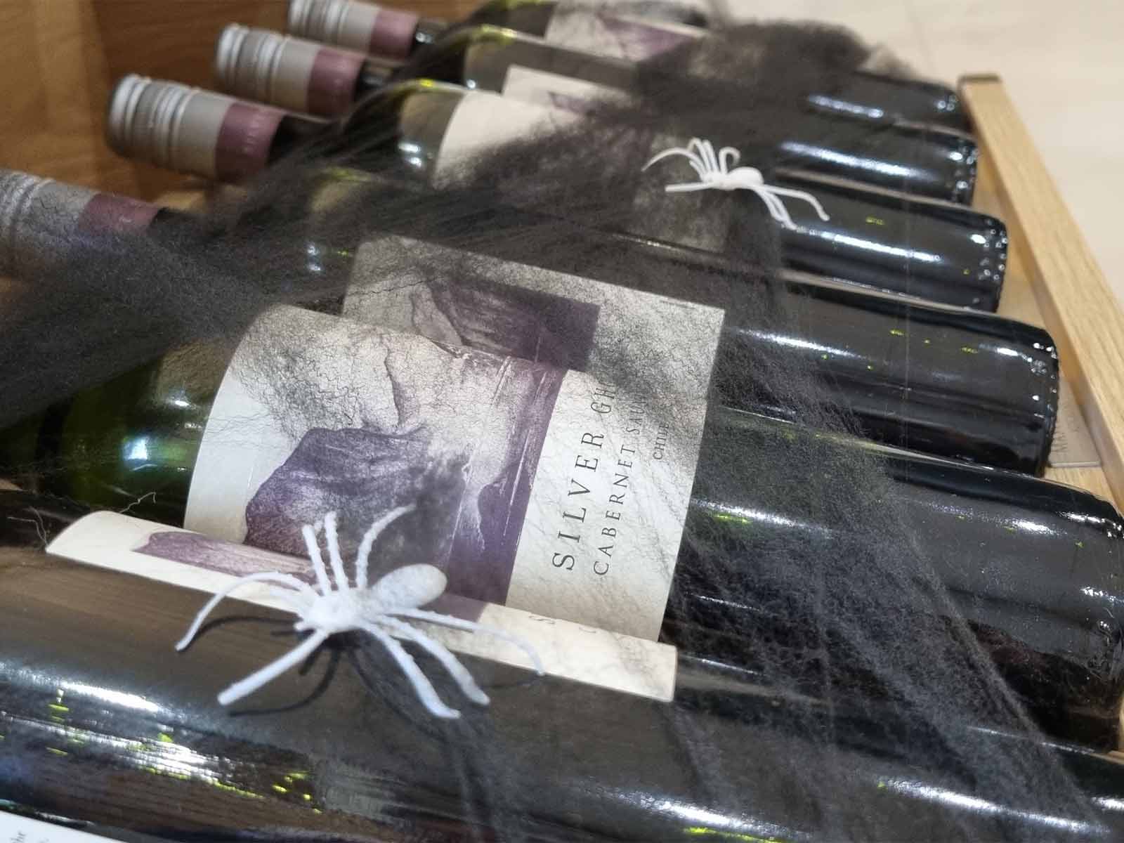 A wine rack with drawer full of bottles and fake spider webs
