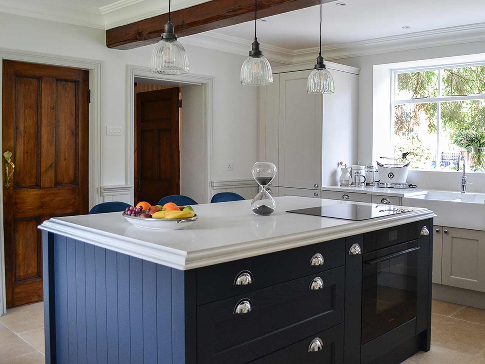 A dark blue kitchen island with white stone worktops