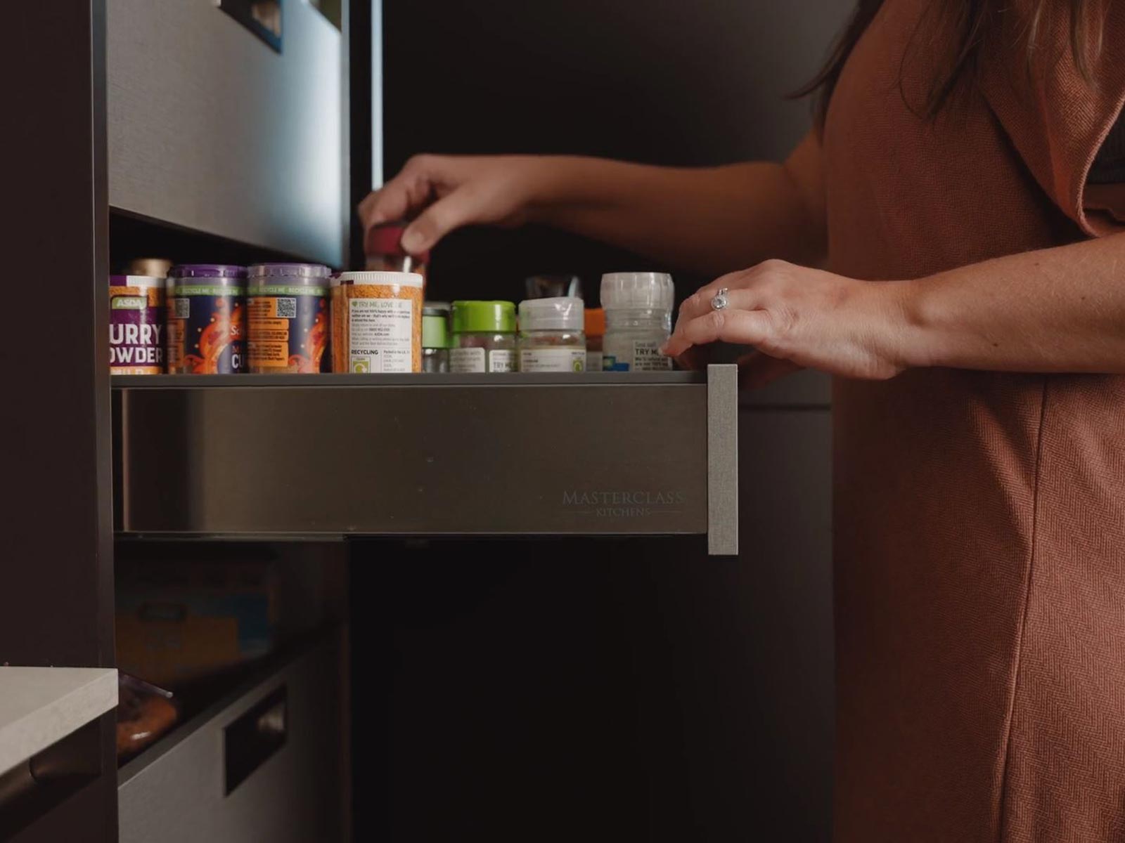 Hidden steel drawers pulled out from a black kitchen cabinet