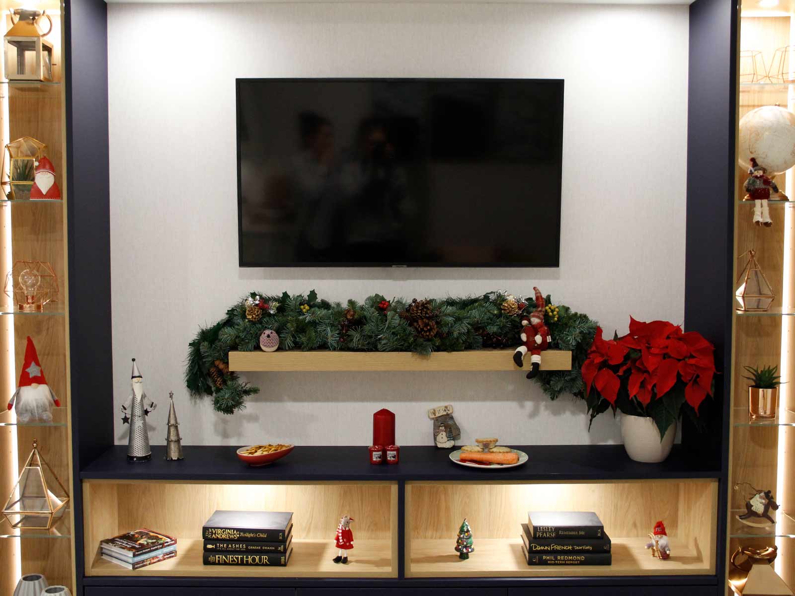 A media wall with cupboards, an oak shelf, a TV and Christmas decorations