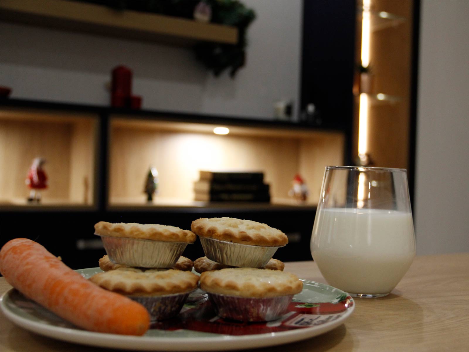 A carrot and mince pies alongside a tumbler of milk on a table