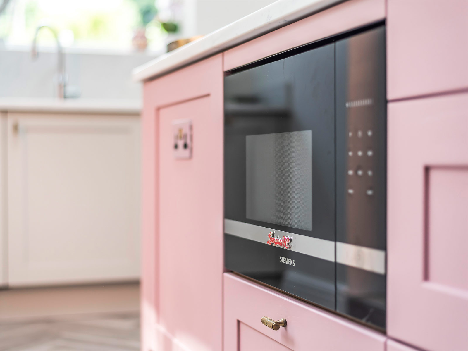 A retro pink kitchen with an inbuilt microwave and an eccentric kitchen vibe