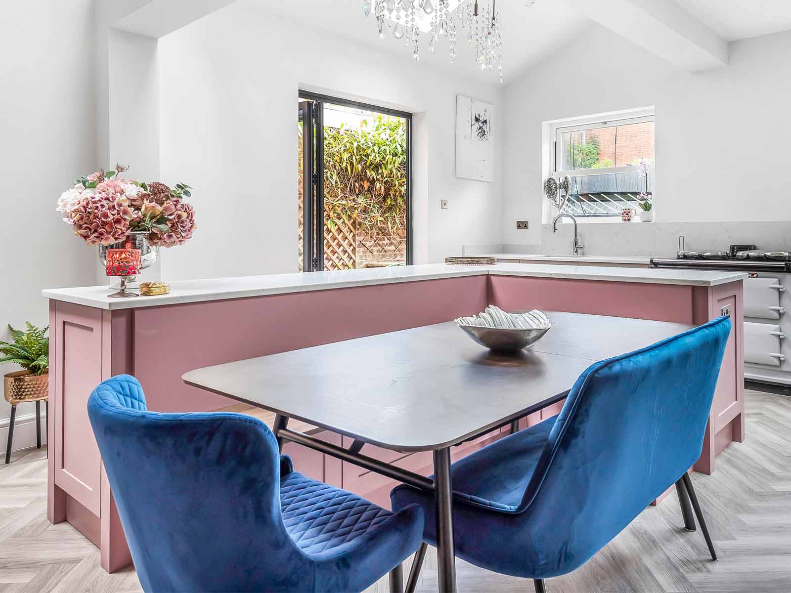 A pink kitchen range with Mexican kitsch bouquets and blue velvet chairs