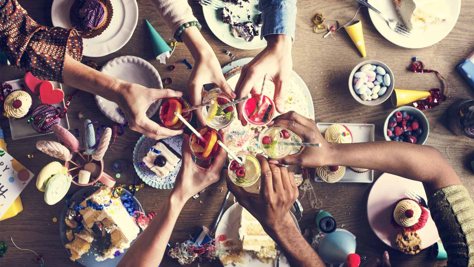 A group of partygoers celebrating afternoon tea with cupcakes and fancy drinks