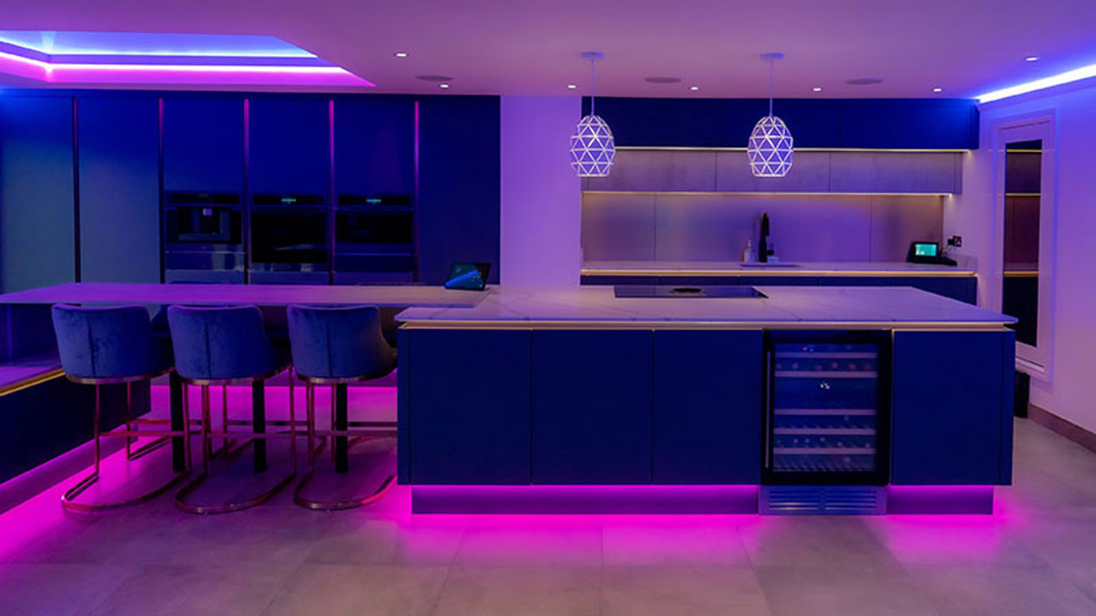 A modern luxury kitchen with a home bar area, a wine fridge and black lights