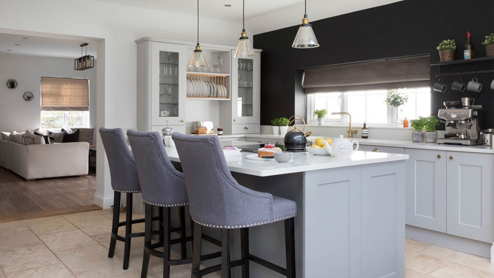 A grey kitchen island with seating in a Shaker kitchen with a dark feature wall