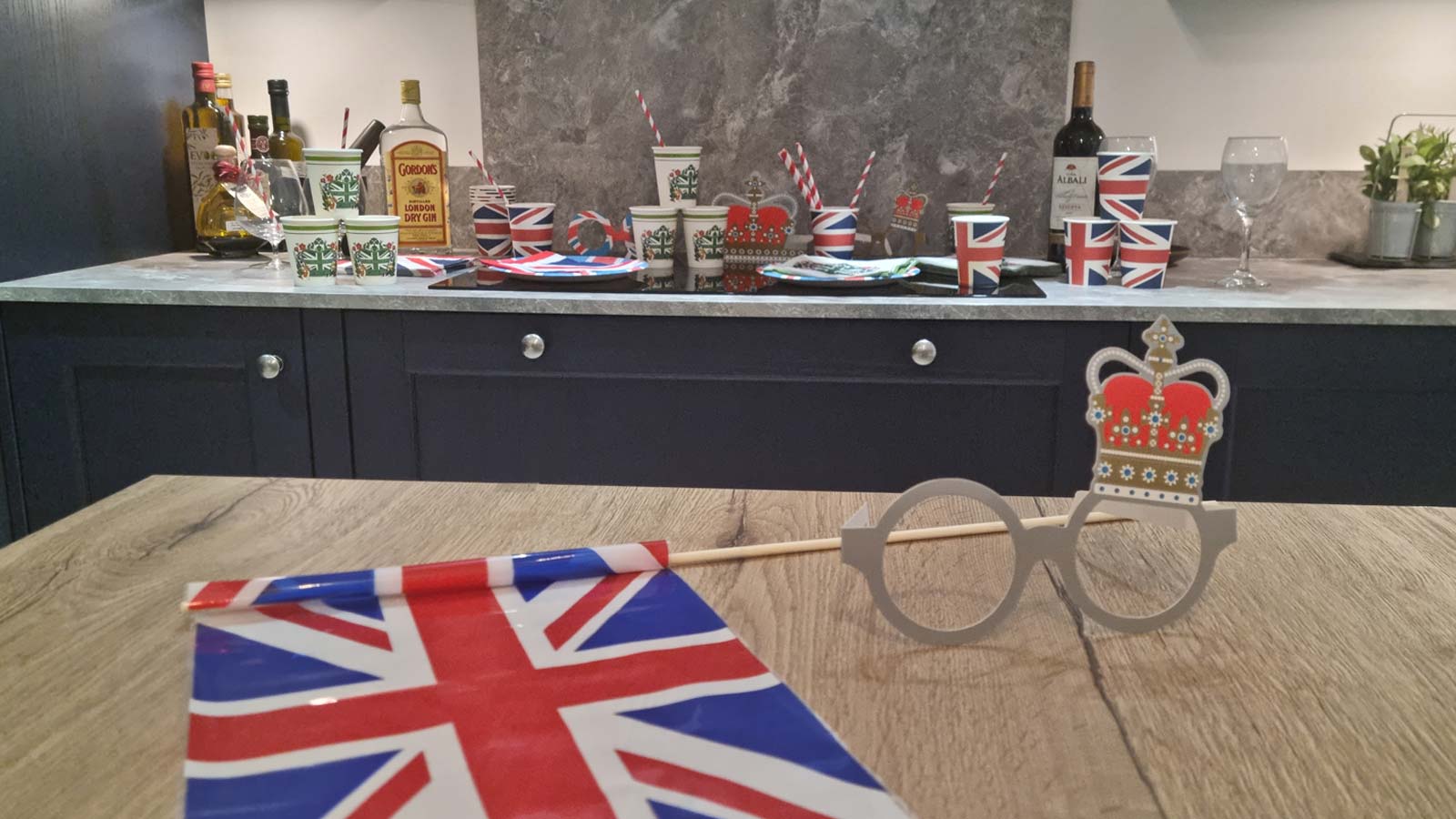 A British flag and crown glasses with a navy Shaker kitchen