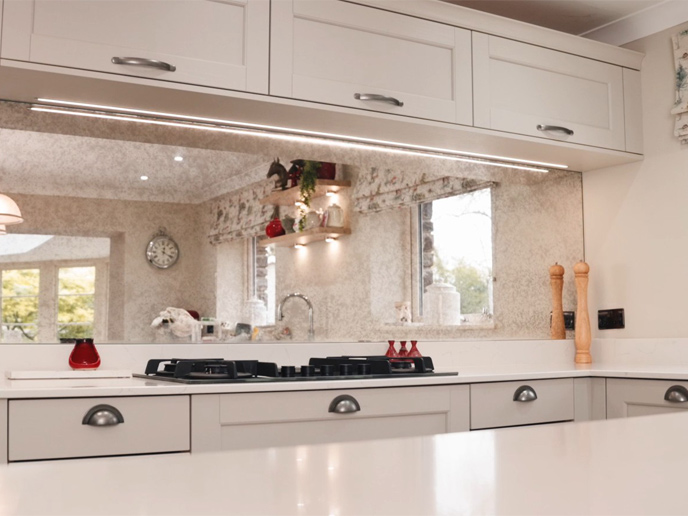 A kitchen hob with a mirrored backsplash in an open kitchen