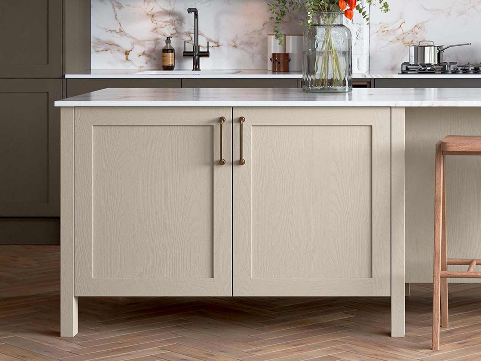 A light brown Shaker kitchen island with a white worktop and bronze D handles
