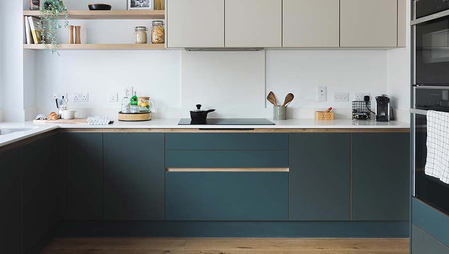 A modern dark kitchen with green and warm grey tones