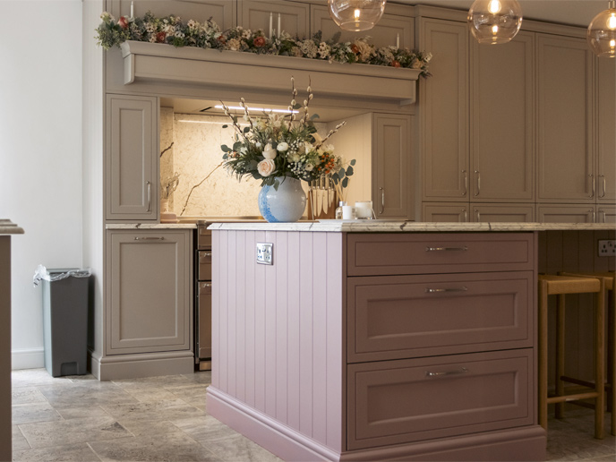 Pink kitchen cabinet drawers in a large island with a marble countertop