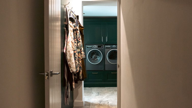 White goods integrated into dark green in-frame utility room cabinets