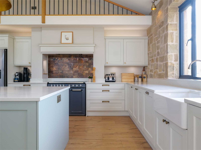 A kitchen with accent wall, kitchen island and Belfast sink