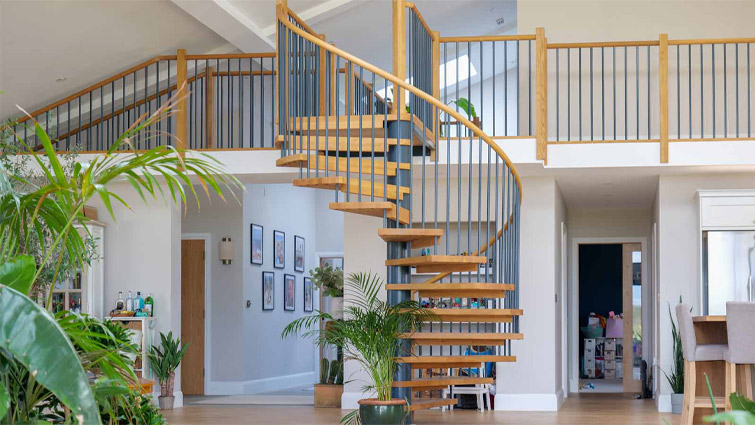 A spiral staircase used to create kitchen zones in a modern open kitchen design