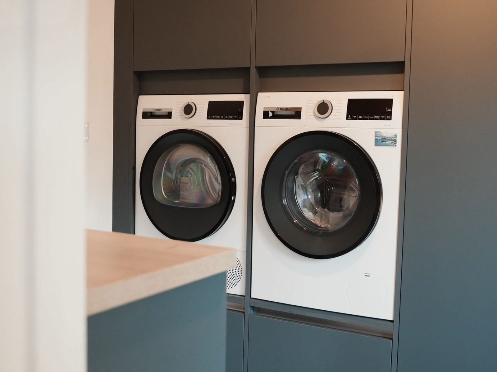 Utility room cupboards holding white goods and space for a vacuum cleaner