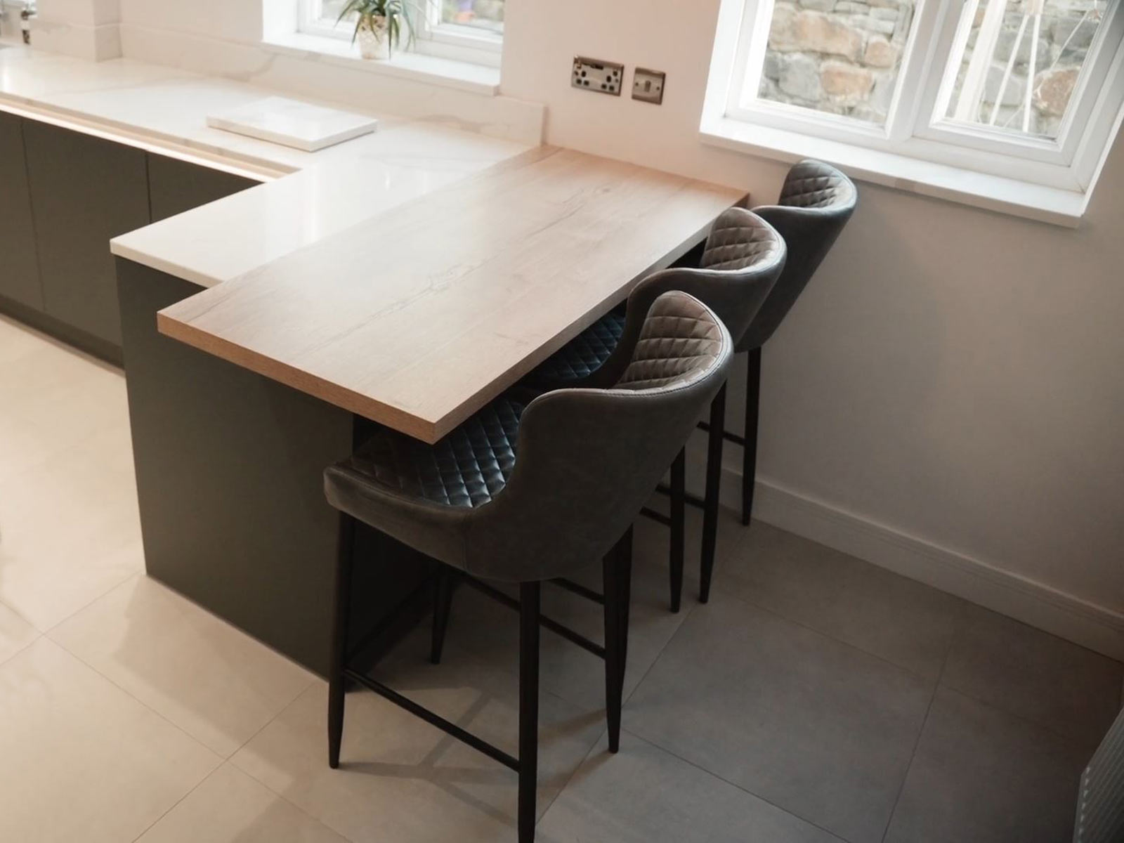 A kitchen peninsula with an oak kitchen worktop, linked to a quartz worktop