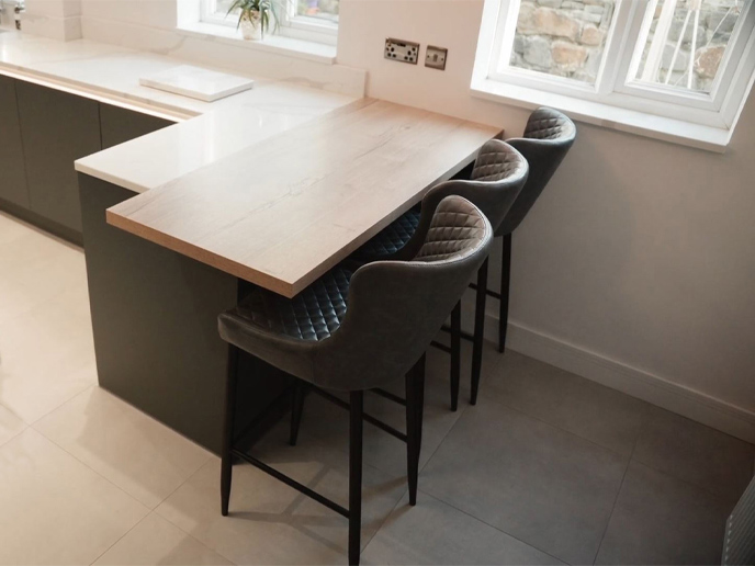 A kitchen peninsula with an oak kitchen worktop, linked to a quartz worktop