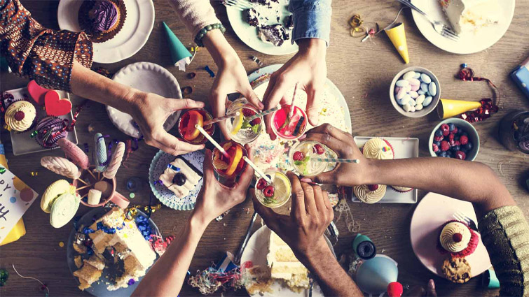 A group of partygoers celebrating afternoon tea with cupcakes and fancy drinks