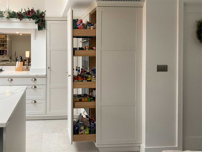 A slab door kitchen with a modern handleless kitchen larder on rails
