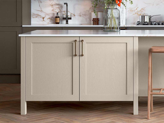 A light brown Shaker kitchen island with a white worktop and bronze D handles