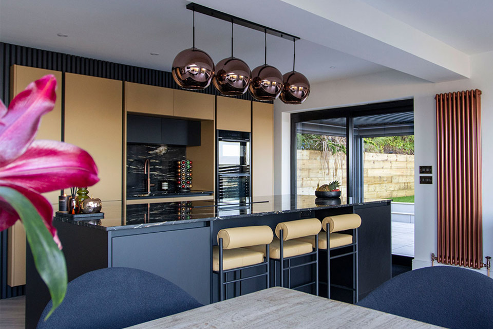 A handleless yellow kitchen design with hanging lights